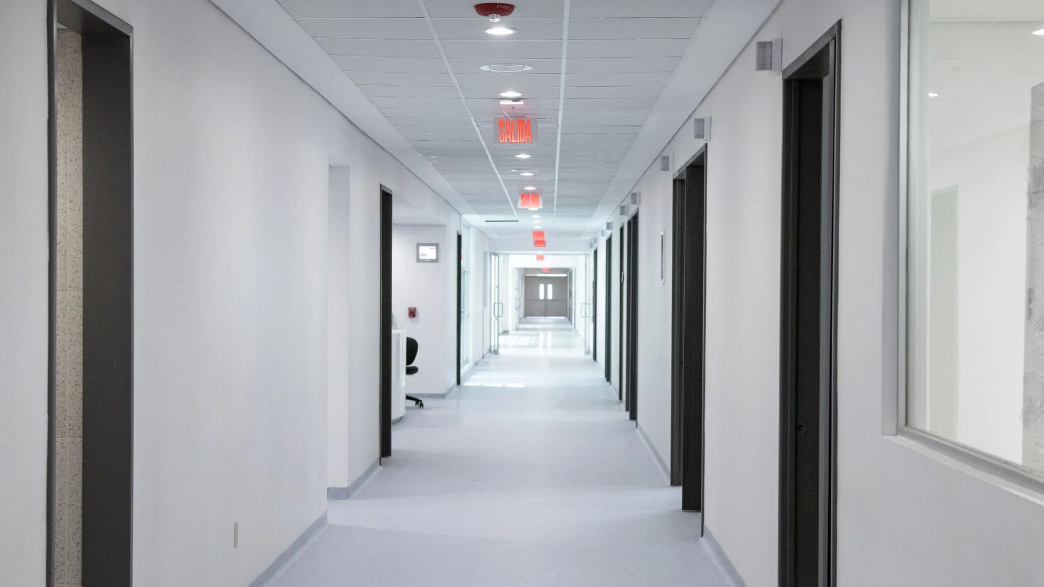 A bright, clean clinic corridor with a row of doors, unoccupied.