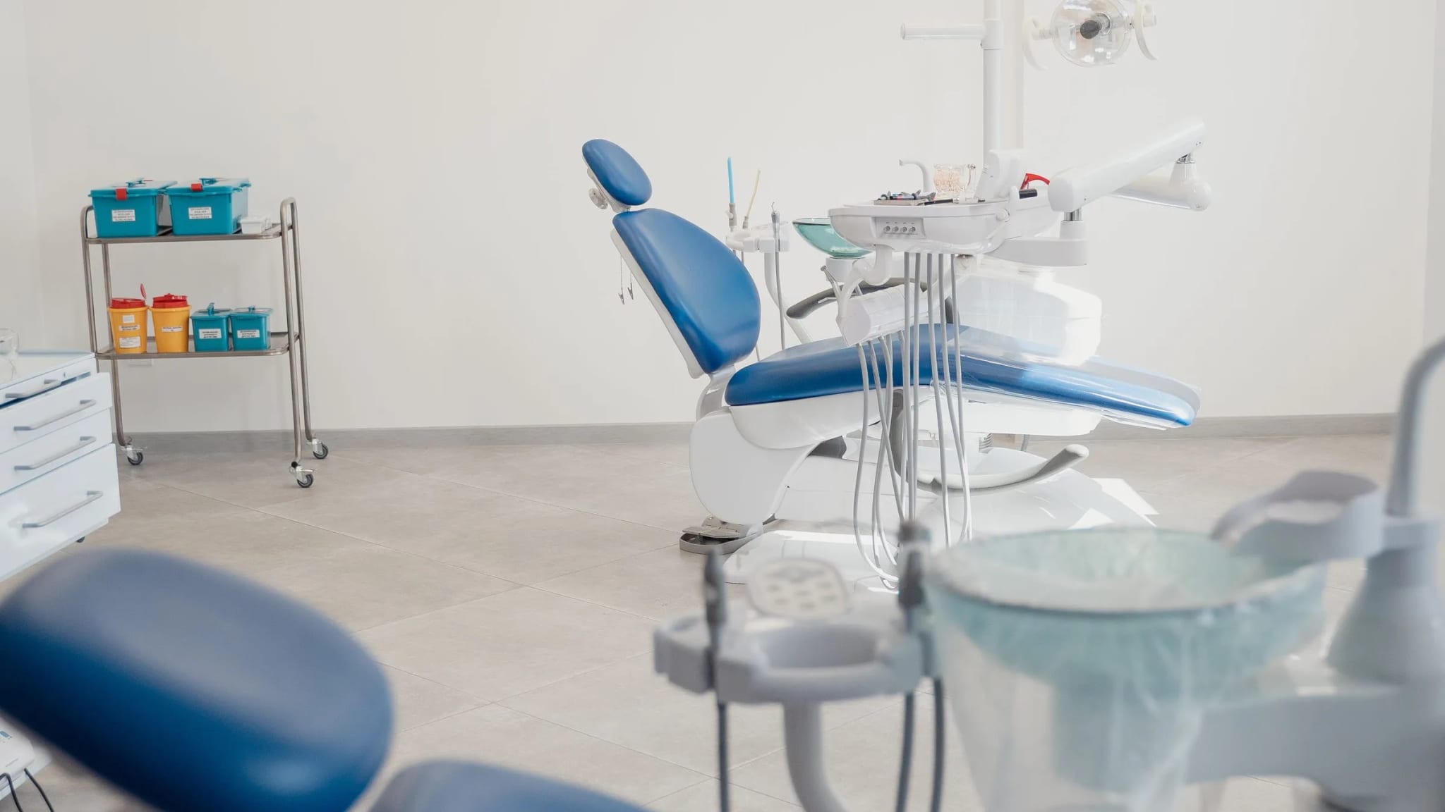 A bright, modern dental practice interior with treatment chairs and equipment against white walls.