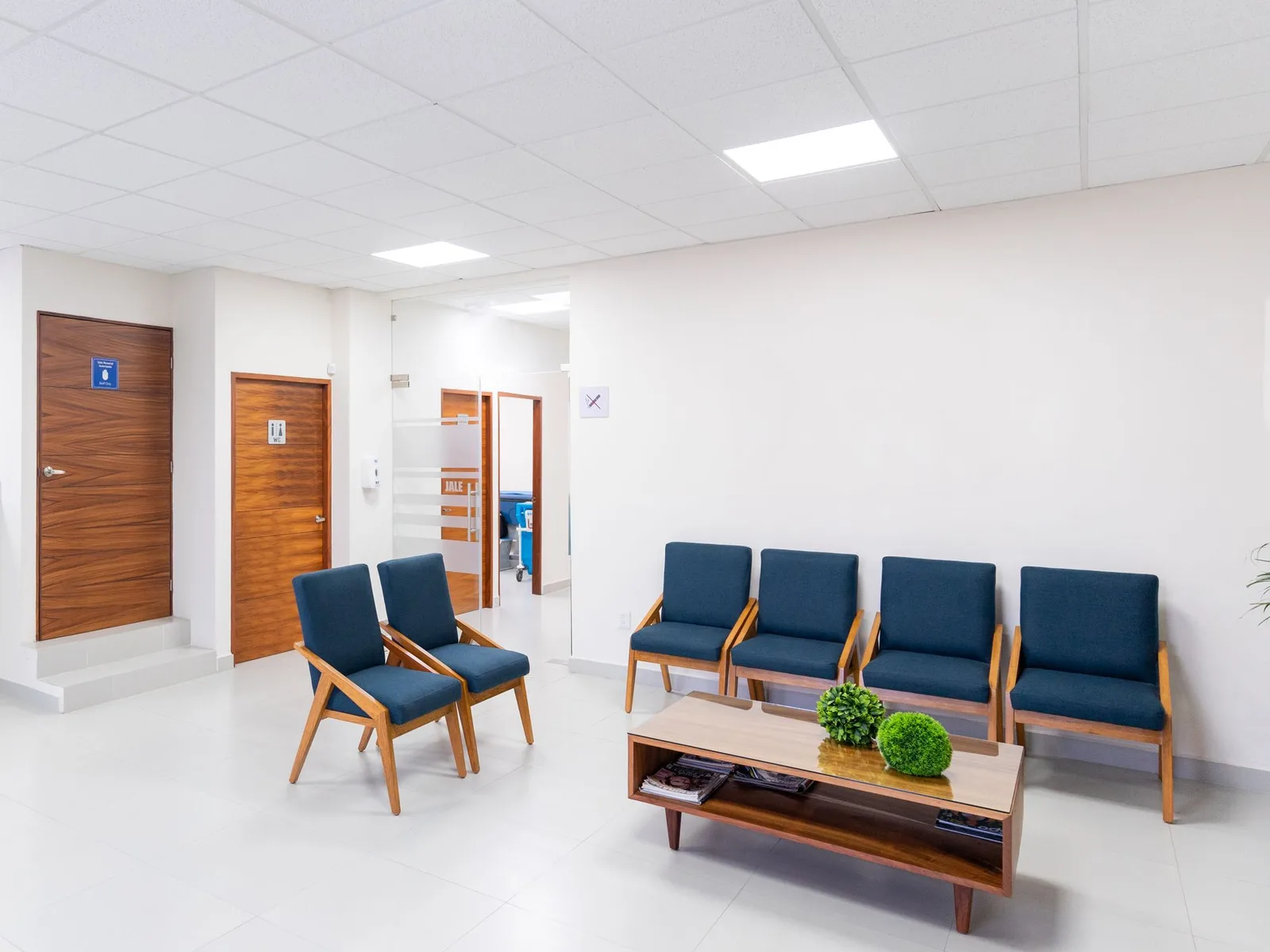 A bright, uncluttered clinic seating area with upholstered chairs and a low table.