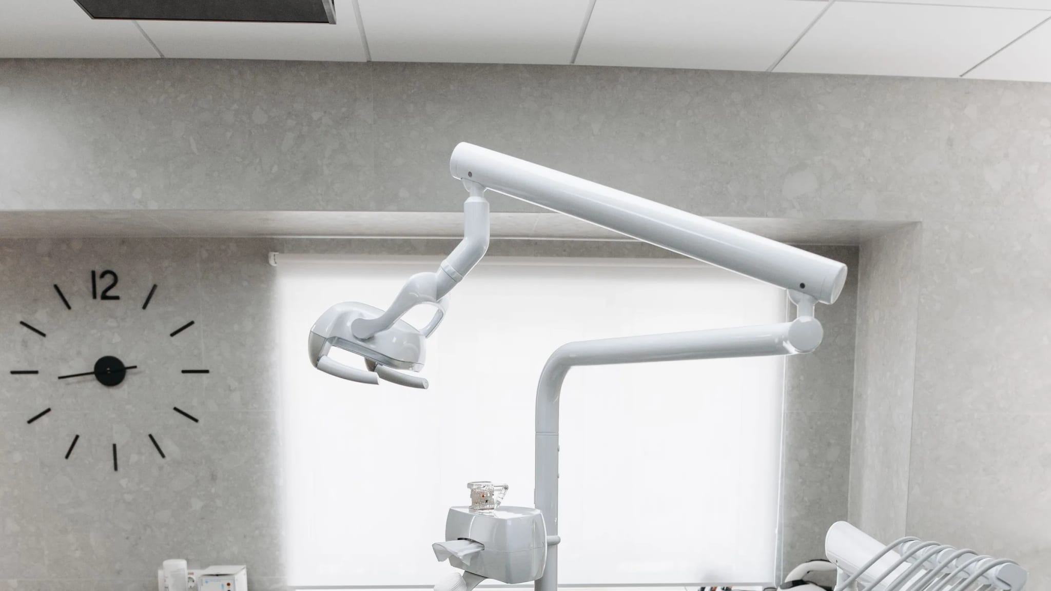 A modern dental treatment room with a reclining chair and overhead light, unoccupied.