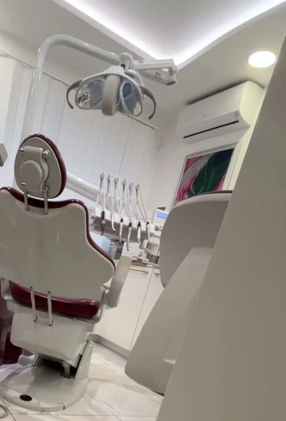 A modern dental treatment room: a reclining dental chair, an overhead examination light and a row of prepared instruments.